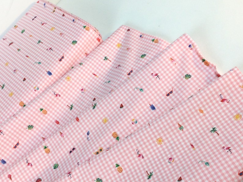 Puede incluir: Tela de cuadros rosa y blanco con un estampado repetido de ilustraciones de verano. El dise&ntilde;o incluye gafas de sol, flamencos, pi&ntilde;as, palmeras, helados y pelotas de playa. La tela est&aacute; doblada, mostrando la repetici&oacute;n del patr&oacute;n.