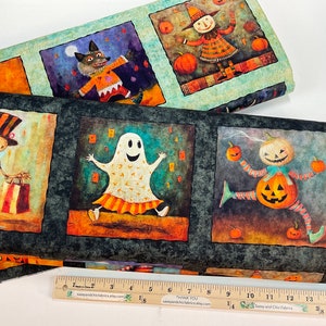 May include: Halloween-themed fabric featuring whimsical illustrations. The design includes a skeleton, a ghost, a pumpkin-headed figure, and a wolf in a square pattern. The fabric is printed with a ruler that measures up to 16 inches.
