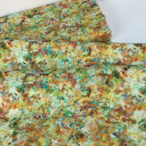 May include: A folded fabric with a colorful, abstract pattern. The design features a mix of colors including yellow, green, brown, orange, blue, and red. The fabric appears to be a lightweight material.