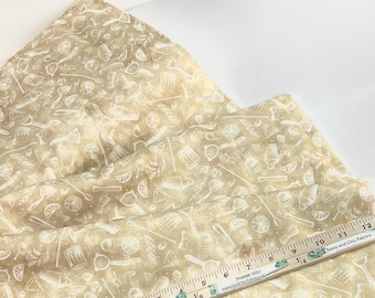 May include: Beige fabric featuring a white cocktail-themed design with lemons, shakers, and bar tools. A wooden ruler displays measurements in inches. The fabric is folded, creating a textured look. Measurements are shown in inches.