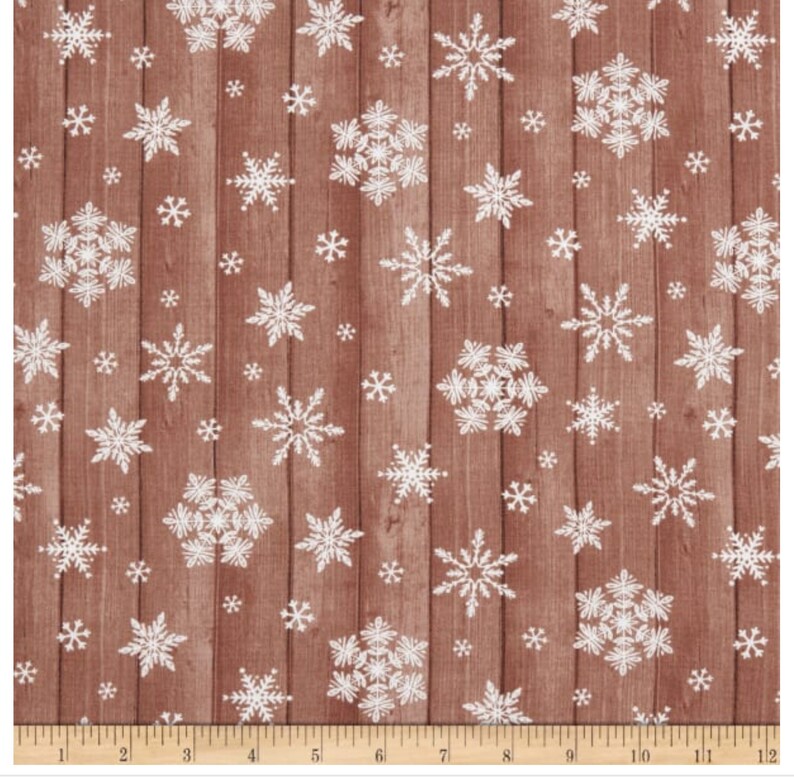 Pu&ograve; includere: Tessuto con un motivo a venature di legno marrone, sovrapposto a fiocchi di neve bianchi di varie dimensioni. I fiocchi di neve sono raggruppati e sparsi sulla superficie, creando un design invernale. Adatto per lavori artigianali natalizi.