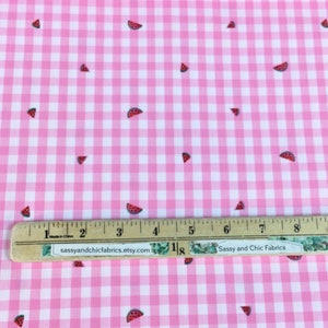 May include: Pink and white gingham fabric with scattered watermelon slice designs. The fabric has a ruler with the text "Sassy and Chic Fabrics etsy.com" on it. The fabric is suitable for sewing projects.