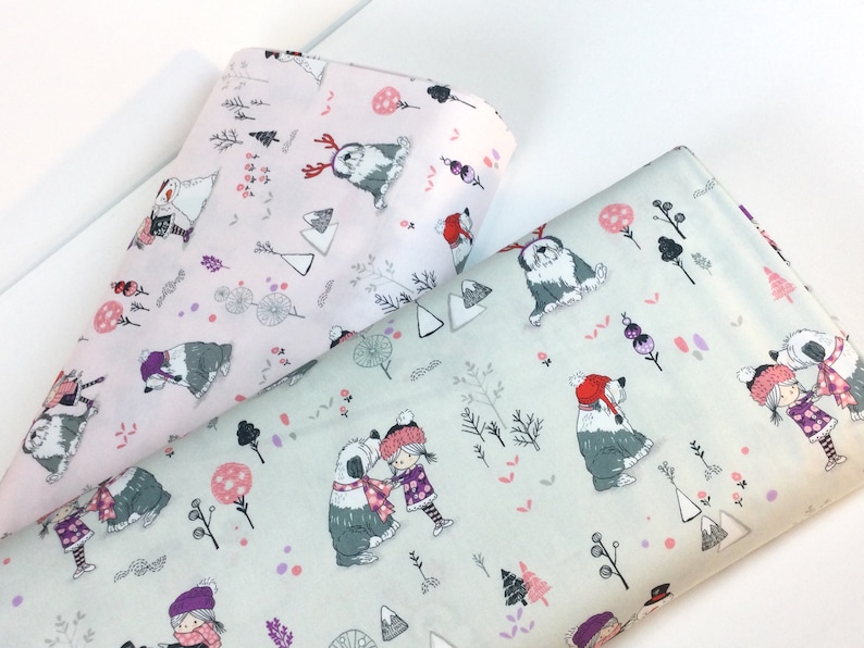 May include: Two rolls of fabric with a winter-themed pattern. One roll is light pink, the other is light green. The pattern features Old English Sheepdogs, children, trees, and other winter elements in shades of gray, pink, purple, and red.