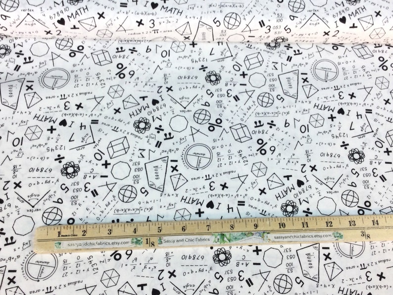 May include: White fabric printed with black math symbols, equations, and the phrase "I ❤️ MATH." Geometric shapes, numbers, and formulas are scattered across the material. A wooden ruler with inch markings is at the bottom.