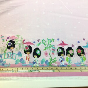 May include: Pink fabric with a repeating border design featuring stylized Japanese dolls, pagodas, lanterns, and butterflies. The dolls wear floral hairpieces and hold parasols. The fabric has a light pink background with small white floral accents.