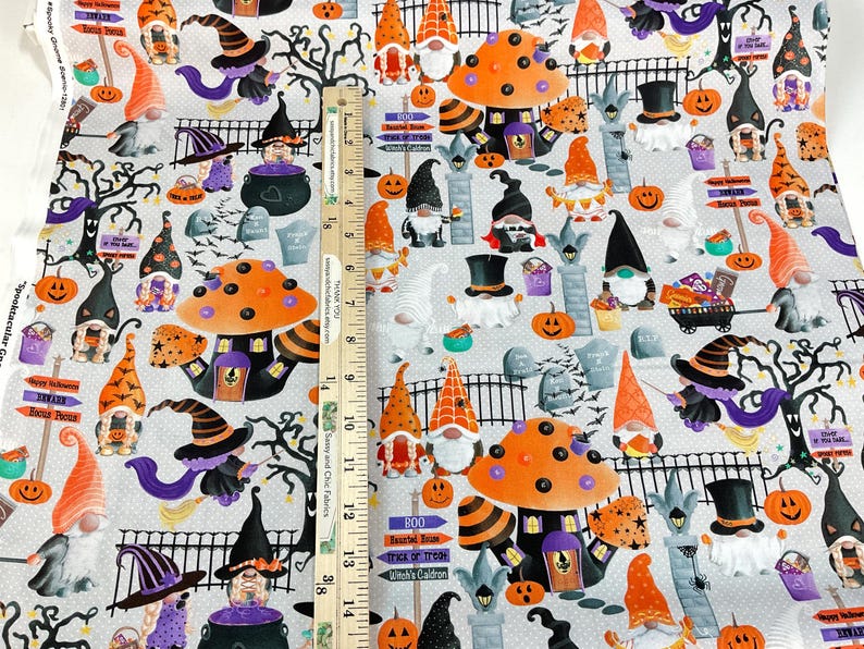 May include: Halloween-themed fabric featuring gnomes, pumpkins, witch hats, and mushrooms in orange, purple, and black on a light gray background. Includes text that reads "Happy Halloween" and "Trick or Treat".