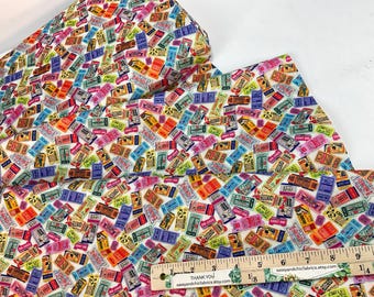 May include: Fabric featuring a repeating pattern of colourful vintage tickets on a white background. The tickets are various colours, including red, blue, green, and yellow. A wooden ruler is placed on the fabric.