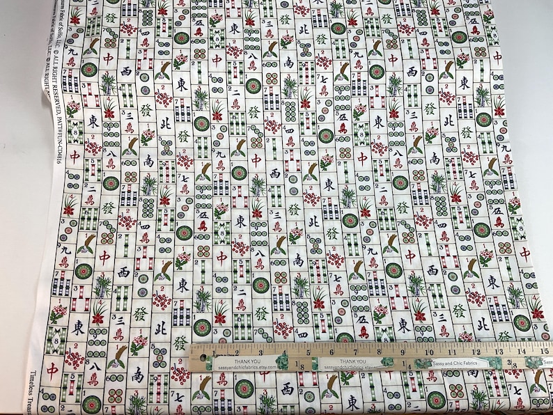May include: White fabric with a repeating pattern of Mahjong tiles, featuring Chinese characters, flowers, and bird illustrations in red, green, and brown. A ruler with the text "THANK YOU" is visible.