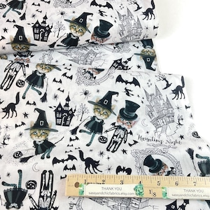 May include: White fabric with a black Halloween-themed print. The design includes cats in witch hats, haunted houses, bats, and skeletons. The text "Haunting Night" is also visible.