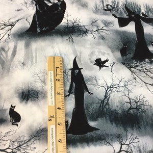 May include: Fabric with a spooky Halloween theme. The design features black silhouettes of witches, cats, and crows against a misty, grayscale forest backdrop. A ruler is placed on the fabric. The text "sassyandchicfabrics.etsy.com" is visible on the ruler.