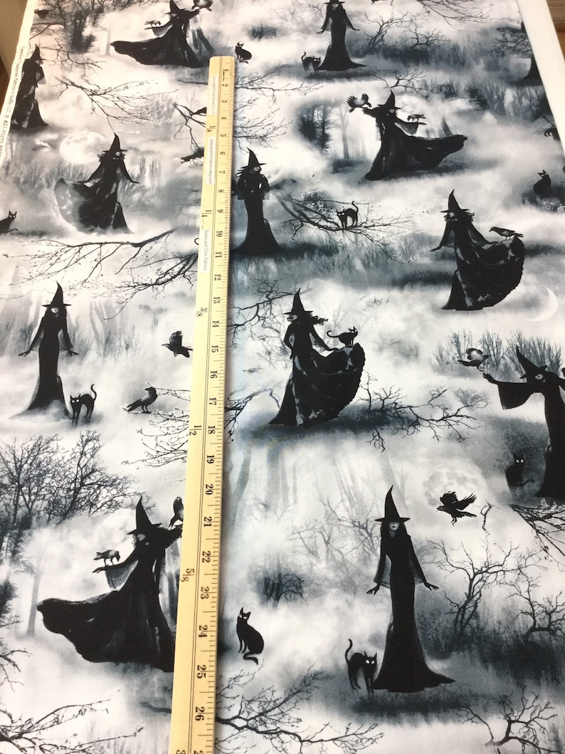 May include: Fabric featuring a repeating pattern of witches in black cloaks and hats, with black cats, crows, and bare tree branches against a misty, moonlit forest backdrop. The ruler shows measurements up to 27 inches.