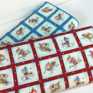 May include: Two fabric pieces with a winter theme. One is red with white squares, each featuring children sledding, skiing, and ice skating. The other is light blue with similar winter scenes. Both fabrics have a repeating pattern.