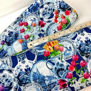 May include: Blue and white fabric with a Delftware design featuring plates, vases, windmills, and tulips. The fabric is decorated with red, yellow, and purple tulips. A wooden ruler measures up to 15 inches.