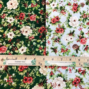 K&ouml;nnte beinhalten: Zwei Stoffmuster mit floralen Mustern. Eines ist dunkelgr&uuml;n mit roten Rosen, wei&szlig;en Blumen und Stechpalmen. Das andere ist hellblau mit dem gleichen floralen Design. Ein Holzlineal zeigt die Ma&szlig;e in Zentimetern an. Der Text "Thank You" und "sassyandchicfabrics.etsy.com" sind sichtbar.