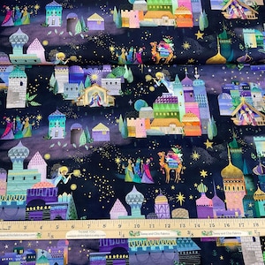 Puede incluir: Tela con un dise&ntilde;o colorido y caprichoso que presenta una escena de la natividad, edificios, estrellas y figuras sobre un fondo azul oscuro. La tela tiene una regla con medidas en cent&iacute;metros.