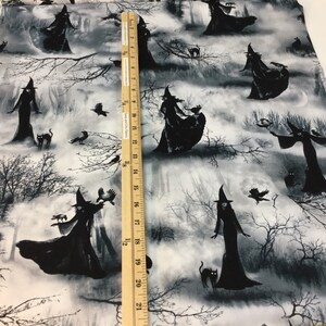 May include: Black and white fabric featuring a repeating pattern of witches in long dresses and pointed hats, with black cats, crows, and bare trees. The fabric has a grayscale color scheme, creating a spooky, Halloween theme.
