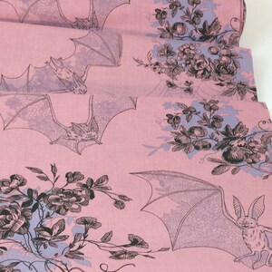 Puede incluir: Tela rosa con un patr&oacute;n repetido de murci&eacute;lagos y dise&ntilde;os florales en negro y morado claro. Los murci&eacute;lagos se representan con las alas extendidas, y las flores incluyen rosas y otras flores. La tela est&aacute; doblada, mostrando m&uacute;ltiples capas.