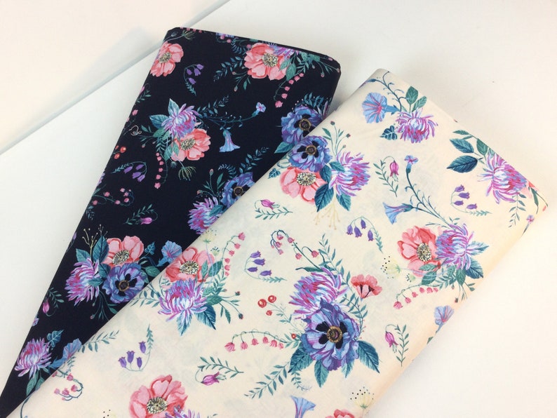 May include: Two rolls of floral fabric. One is navy blue with pink, purple, and blue flowers. The other is off-white with the same floral pattern. The fabric features detailed botanical illustrations.