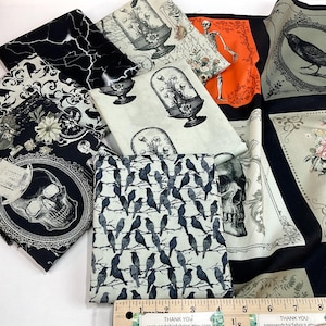 May include: Assortment of fabric squares with gothic and Halloween-themed patterns. Designs include skulls, ravens, skeletons, and floral arrangements in black, white, and orange. A ruler is visible.