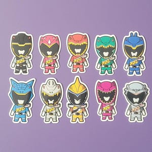 May include: Set of ten colorful cartoon Power Rangers stickers. Each sticker features a different Ranger with a unique helmet design. The Rangers are in various poses, including standing, jumping, and striking a fighting pose.