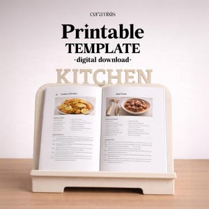 Puede incluir: Un libro de cocina abierto sobre un atril crema. El libro de cocina presenta recetas de pollo al limón y estofado de ternera. El atril tiene la palabra "KITCHEN" y las palabras "Printable TEMPLATE - digital download-".