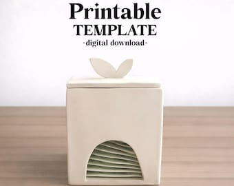 May include: A white square ceramic box with a lid featuring a leaf-shaped handle. The front has an arched cutout revealing stacked light green plates inside. Text above reads: ceramixis Printable TEMPLATE digital download.