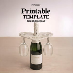Puede incluir: Un soporte blanco en forma de corazón para botella de vino con las palabras "Best Mom" y dos copas de vino. Una botella de vino verde está en el centro. La imagen también incluye el texto "Printable TEMPLATE digital download".