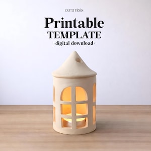 May include: A beige ceramic house-shaped candle holder with a conical roof and arched window cutouts. The text above reads ceramixis Printable TEMPLATE digital download. A small glowing tea light candle is visible inside the structure.