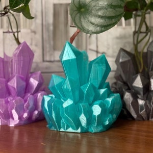May include: Three crystal-shaped planters in purple, teal, and gray. Each planter has a small plant growing out of the top.