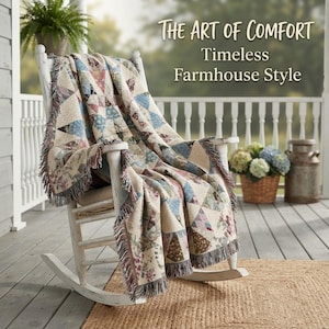 May include: A white wooden rocking chair draped with a woven throw blanket featuring a multi-colored geometric star pattern and fringed edges. The text "THE ART OF COMFORT Timeless Farmhouse Style" is displayed in the upper right corner of the image.