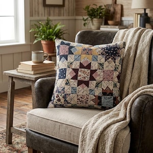Könnte beinhalten: Ein quadratisches Zierkissen mit einem Patchwork-Steppmuster und einem Sternmotiv in Marineblau, Burgunderrot, Gelb und Creme. Der Stoff zeigt verschiedene florale und geometrische Drucke, die ein strukturiertes, mehrfarbiges Erscheinungsbild erzeugen.