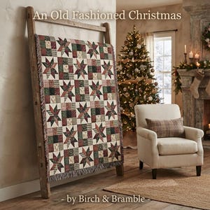 May include: A woven throw blanket featuring a repeating patchwork pattern of eight-pointed stars and checkered squares in shades of red, green, and cream. The blanket is draped over a wooden ladder. Text reads: An Old Fashioned Christmas by Birch & Bramble.