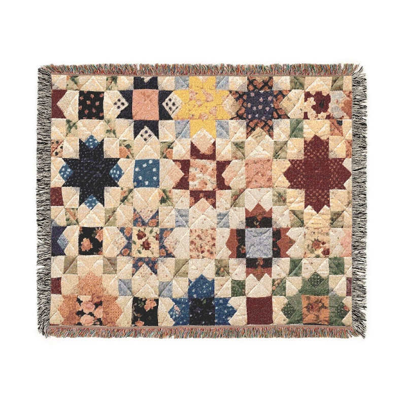 May include: A woven throw blanket featuring a repeating star quilt pattern in a variety of colors including deep red, navy blue, yellow, and cream. The blanket has a textured surface with a fringe border along all four edges of the rectangular fabric.