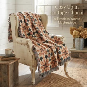 May include: A woven throw blanket with a geometric star and diamond pattern in shades of rust, cream, and charcoal gray, featuring fringed edges. The blanket is draped over an off-white armchair. Text reads: Cozy Up in Cottage Charm A Timeless Woven Masterpiece.