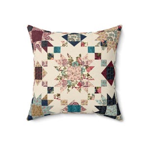 May include: A square throw cushion featuring a patchwork quilt design with a central star motif. The fabric displays a variety of floral and geometric patterns in shades of cream, burgundy, teal, navy blue, and soft pink, arranged in a star pattern.