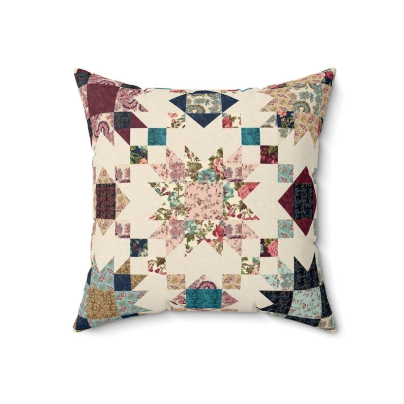 May include: A square throw cushion featuring a patchwork quilt design with a central star motif. The fabric displays a variety of floral and geometric patterns in shades of cream, burgundy, teal, navy blue, and soft pink, arranged in a star pattern.