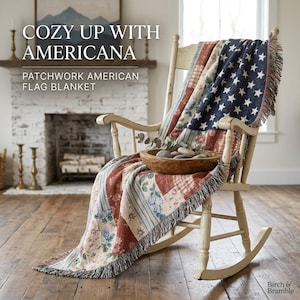 May include: A cream-colored wooden rocking chair draped with a woven patchwork blanket featuring a blue field of white stars and red and white stripes with floral patterns. A wooden bowl containing smooth stones sits on the blanket.
