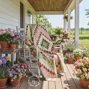 May include: A white wooden rocking chair draped with a patchwork quilt featuring a geometric diamond pattern in shades of pink, green, and cream. The chair is surrounded by numerous terracotta pots filled with blooming pink, purple, and white flowers.