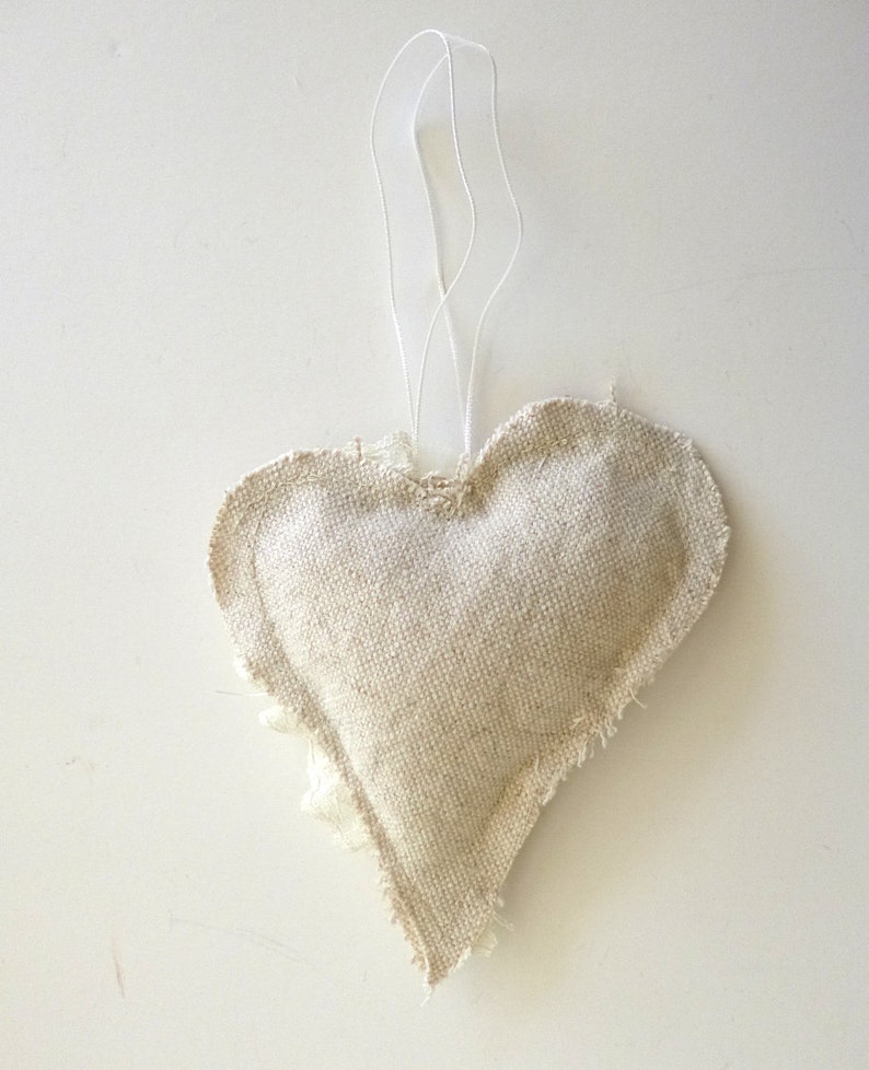 May include: A beige heart-shaped fabric ornament with a frayed edge and a white string for hanging.