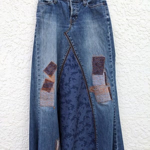 May include: A long denim skirt with patchwork details. The skirt is blue with brown and white stitching. The skirt has a blue floral lining.