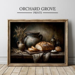 May include: A framed print featuring a still life with bread, pottery, and wheat. The image includes a loaf of bread, sliced bread, a large ceramic pot, and a small vase with wheat stalks. The text "ORCHARD GROVE PRINTS" is at the top.