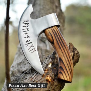 May include: A stainless steel pizza axe with a curved blade and a wooden handle. The blade has etched runes. The handle is made of wood with a striped pattern. The text "Pizza Axe Best Gift" is at the bottom.