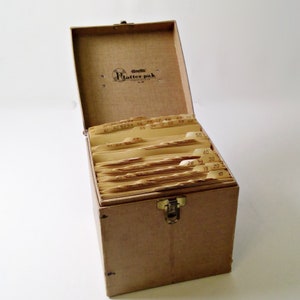 May include: A brown cardboard box with a metal latch. The box is labeled "Gonnella Platter Pak" and has a series of numbered dividers inside. The dividers are labeled with numbers from 10 to 70.