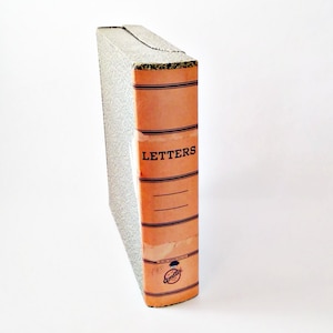 May include: Vintage orange and black "Letters" file box. The box has a textured, patterned gray side and a spine with the word "Letters" in black. The spine has black horizontal lines and the Amity logo.