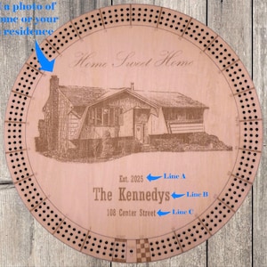 May include: A round wooden cribbage board with a house illustration and the text "Home Sweet Home." It includes the family name, address, and the year 2025. The board has numerous holes for pegging.