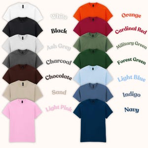 Op de afbeelding: Een verzameling t-shirts met korte mouwen in diverse kleuren, waaronder wit, zwart, asgrijs, houtskool, chocolade, zand, lichtroze, oranje, kardinaalrood, legergroen, bosgroen, lichtblauw, indigo en marineblauw. De kleuren zijn gelabeld.