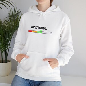 Puede incluir: Sudadera con capucha blanca con un gráfico negro que dice "BOOST LOADING..." con una barra de progreso debajo. La barra de progreso está llena de rojo, naranja, amarillo, verde y gris.