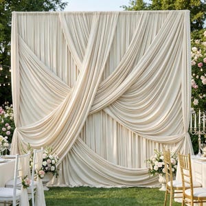 Peut inclure: Toile de fond en tissu drapé de couleur crème pour un événement en plein air. Le tissu est disposé en plis fluides et en motifs croisés. La toile de fond est installée sur une pelouse verte, avec des compositions florales et des chaises au premier plan.