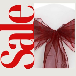 Puede incluir: Falda de silla de color burdeos hecha de tela transparente, atada en un lazo. La falda es un acento decorativo para bodas y eventos especiales.
