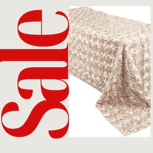 May include: A champagne-colored satin tablecloth with a rose pattern. The tablecloth is made of a soft, luxurious fabric and is perfect for adding a touch of elegance to any event.